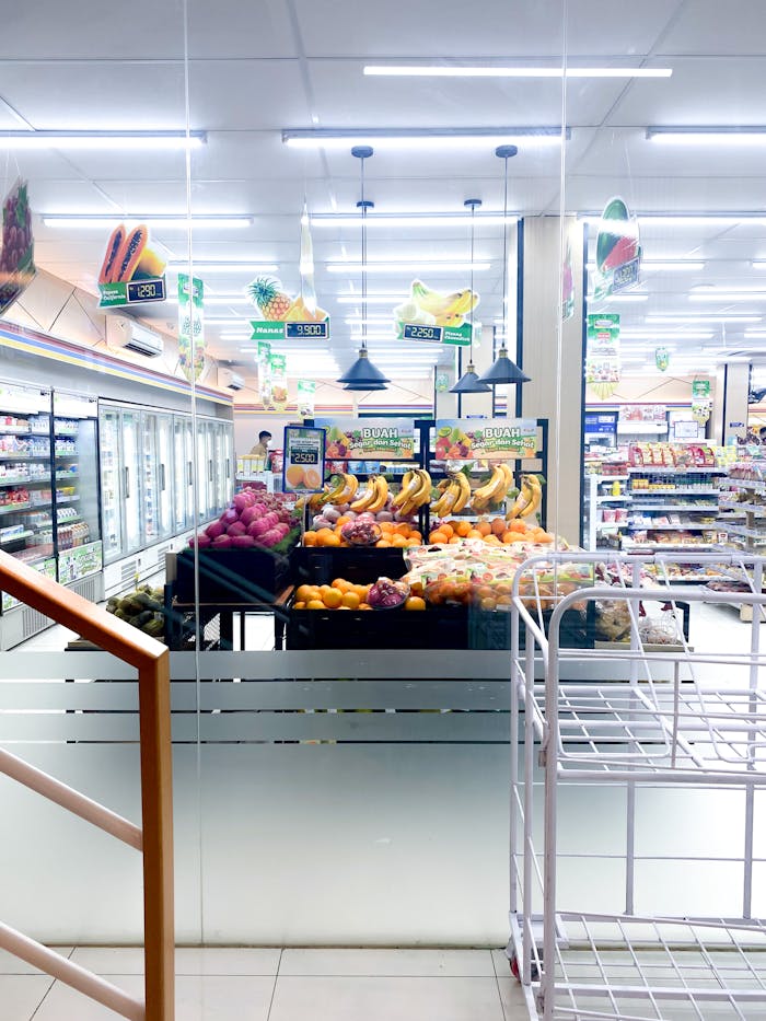 pexels-photo-12340541 Vibrant fruit display in a well-lit supermarket aisle with fridges and shelves.