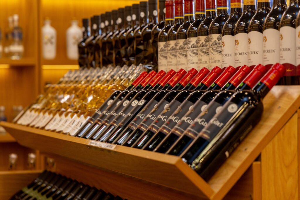 pexels-photo-30447488 Close-up of diverse wine bottles arranged on a wooden shelf display.